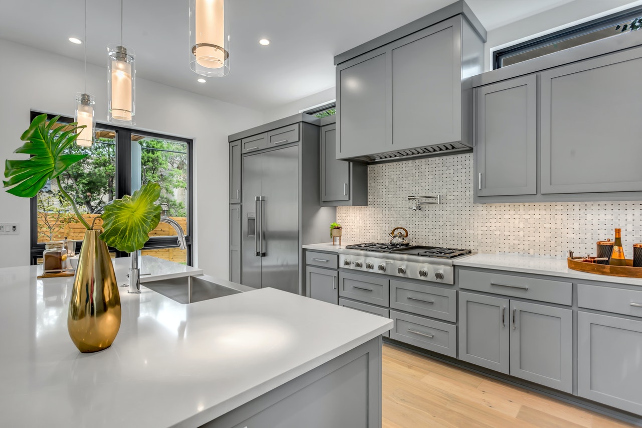 the white kitchen with a window, a vase, and light fixtures